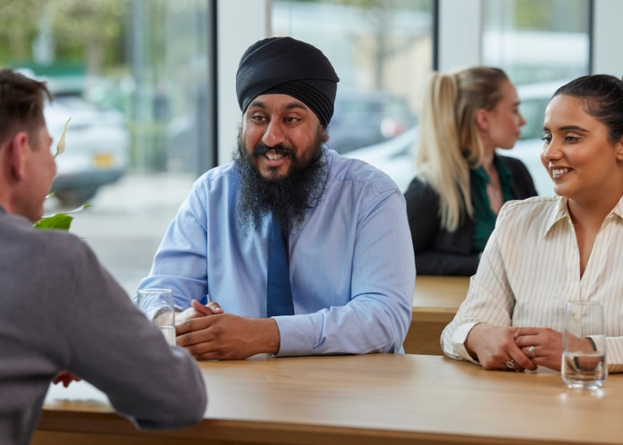 Three Enterprise Mobility team members sitting down at a table networking