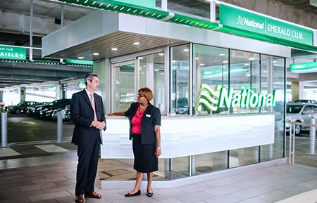 Two National Car Rental customer service agents talking in an airport car rental branch. 